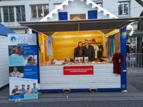 Deux bénévoles de PSE Ain-Rhône-Isère devant leur stand lors d'un marché de Noël