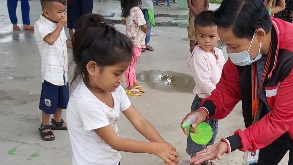 Un éducateur de PSE donne du gel hydroalcoolique a une petite fille pour qu'elle se lave les mains