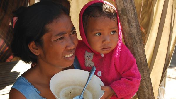 Une mère et son bébé avec un bol vide dans un quartier pauvre