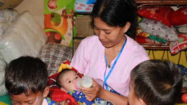 Phalla, l'une des responsables de la PMI de PSE, donne le biberon à un bébé