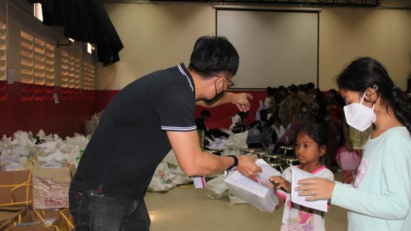 Un travailleur social de PSE aident deux petites filles à récupérer le matériel scolaire