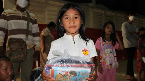 Une petite fille avec le matériel scolaire reçu pour l'année 2023