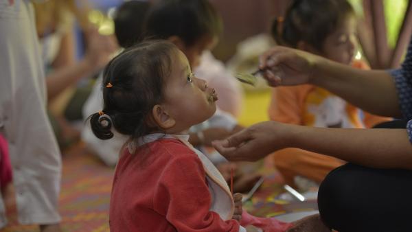 On donne à manger à une petite fille au centre de nutrition de PSE