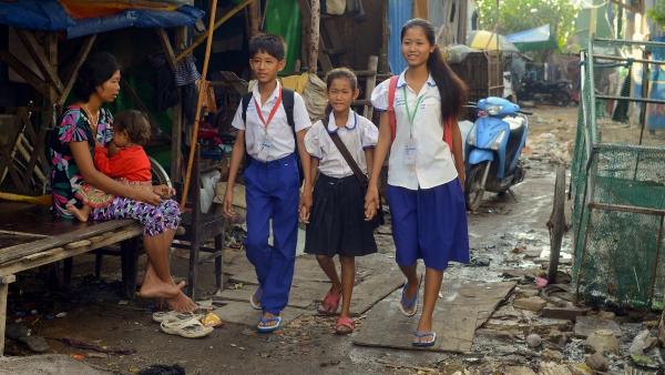 Des enfants en uniforme scolaire traversent le quartier de grande misère dans lequel ils vivent