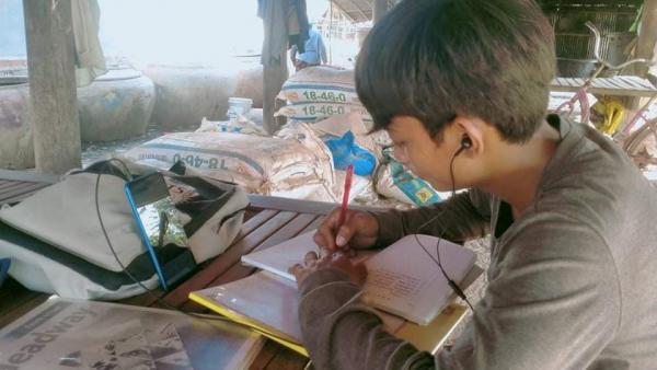 Un élève continue d'étudier chez lui en se connectant aux cours à distance via un smartphone prêté p