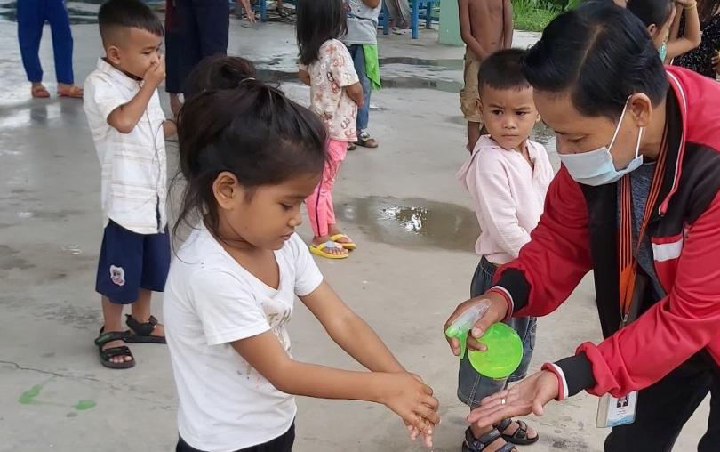 Un éducateur de PSE donne du gel hydroalcoolique a une petite fille pour qu'elle se lave les mains