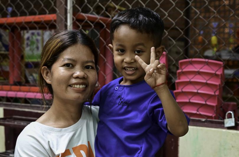 Pich, une maman de l'atelier couture, porte son fils Daravisal dans ses bras