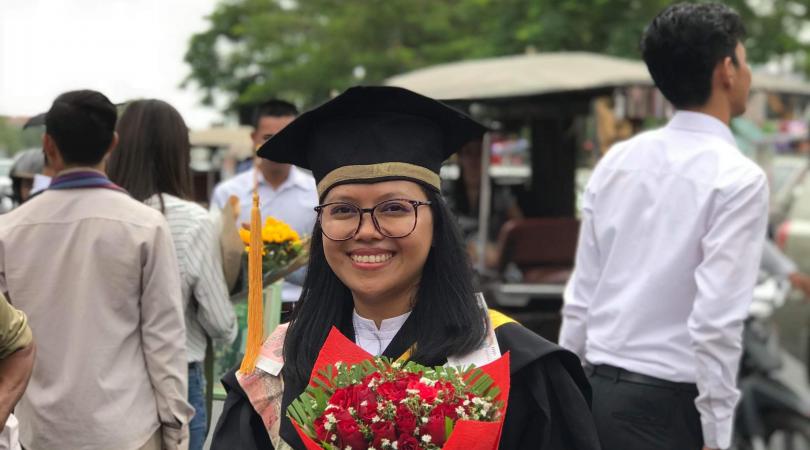 Sorya habillée pour sa remise de diplôme et avec un bouquet de fleurs dans les mains