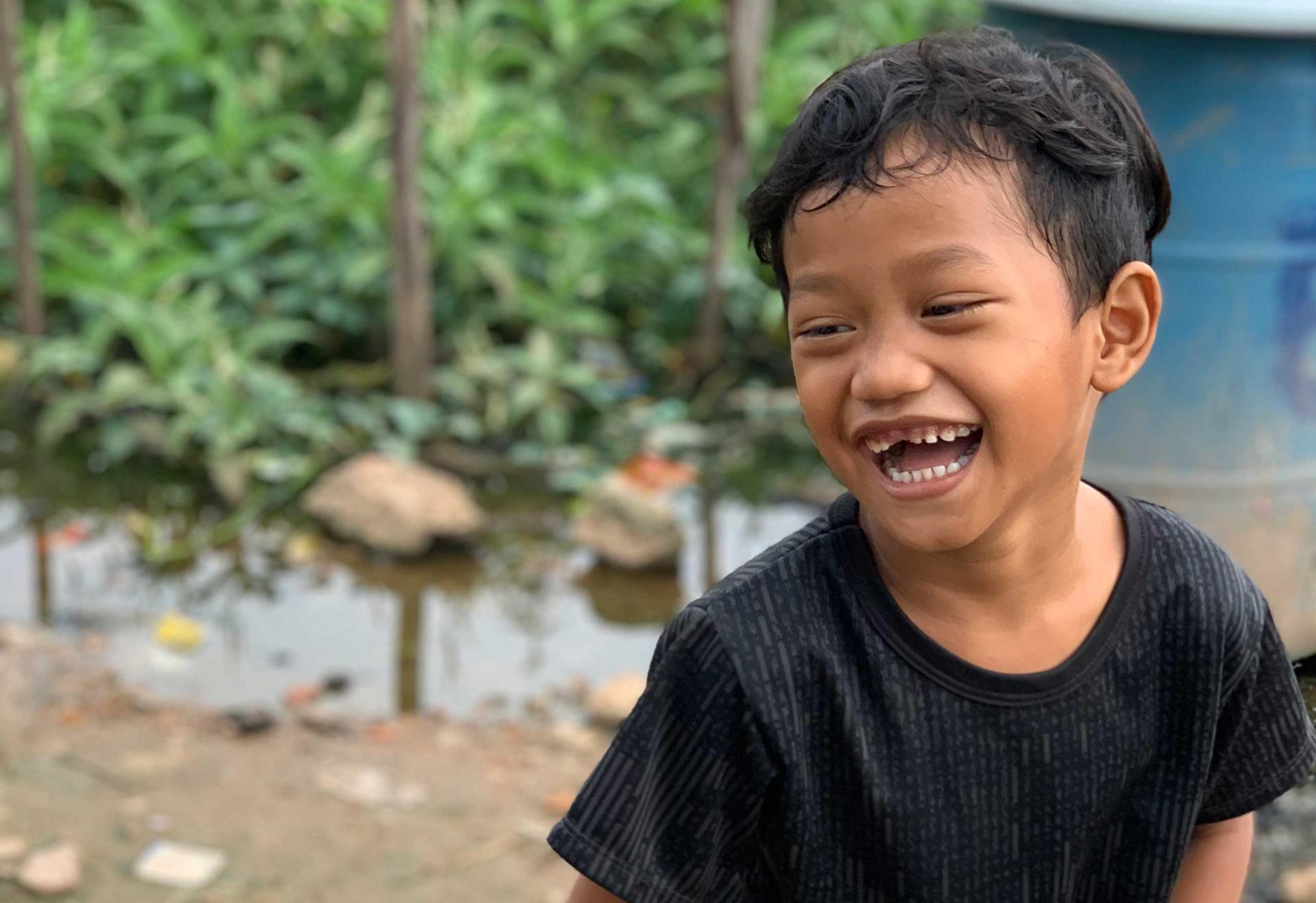 Un petit garçon rit dans le bidonville de Prek Thom