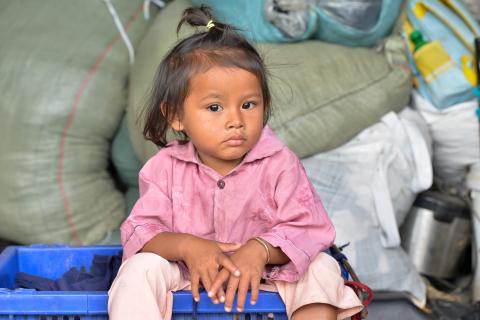 Une petite fille assise devant des sacs de riz distribués par PSE Une petite fille assise devant des sacs de riz distribués par PSE