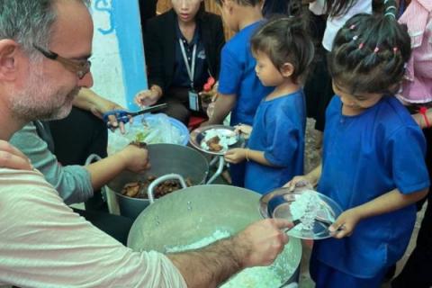 Un bénévole de PSE Hong Kong distribue des repas aux enfants des paillotes de PSE Un bénévole de PSE Hong Kong distribue des repas aux enfants des paillotes de PSE