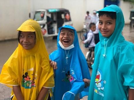 Des enfants souriant portant des imperméables distribués par PSE Des enfants souriant portant des imperméables distribués par PSE