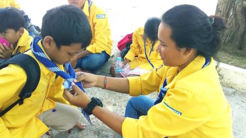 Une scout aidant un enfant à nouer son foulard