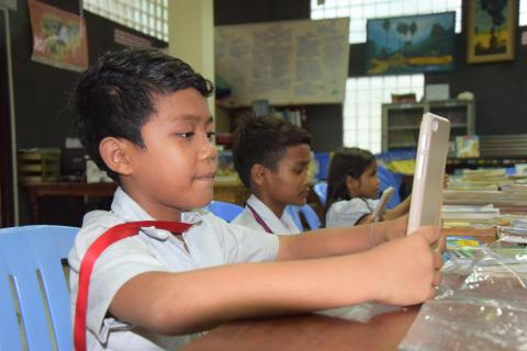 Des élèves utilisent une tablette dans la bibliothèque de PSE Des élèves utilisent une tablette dans la bibliothèque de PSE