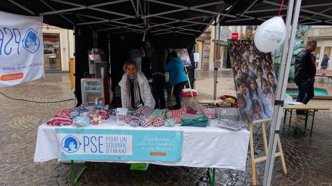 Une bénévole tient un stand PSE Une bénévole à une vente solidaire pour PSE