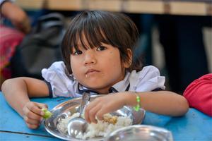 Une petite fille en train de déjeuner à la cantine de PSE Une petite fille en train de déjeuner à la cantine de PSE