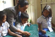Une enseignante aide un enfant à écrire sur son ardoise